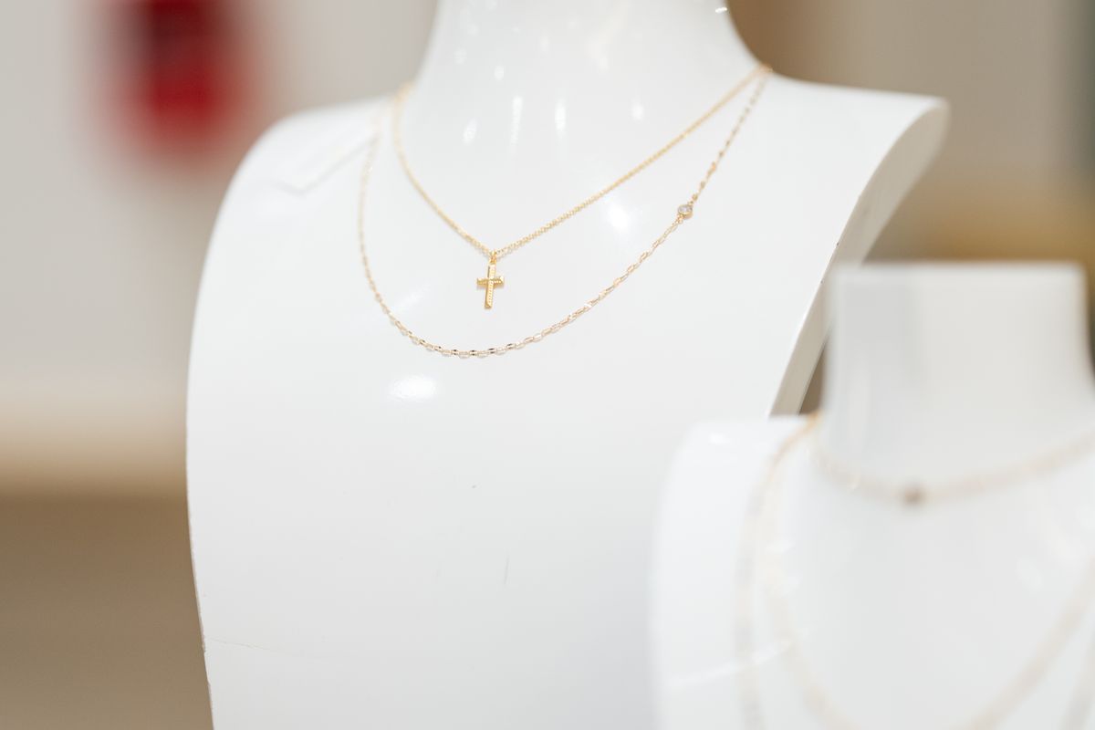 A delicate gold necklace on a white jewelry bust