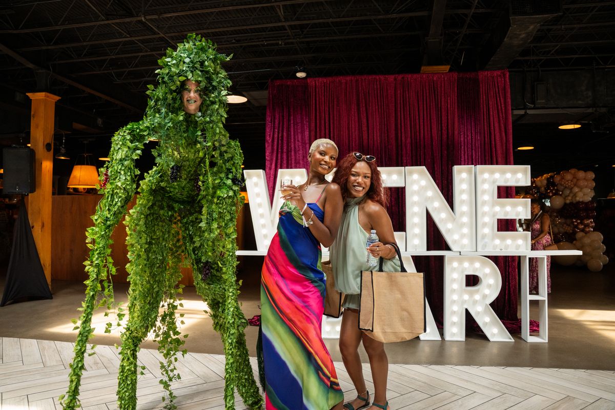 A costumed stilt walker posing with guests at the wine bar